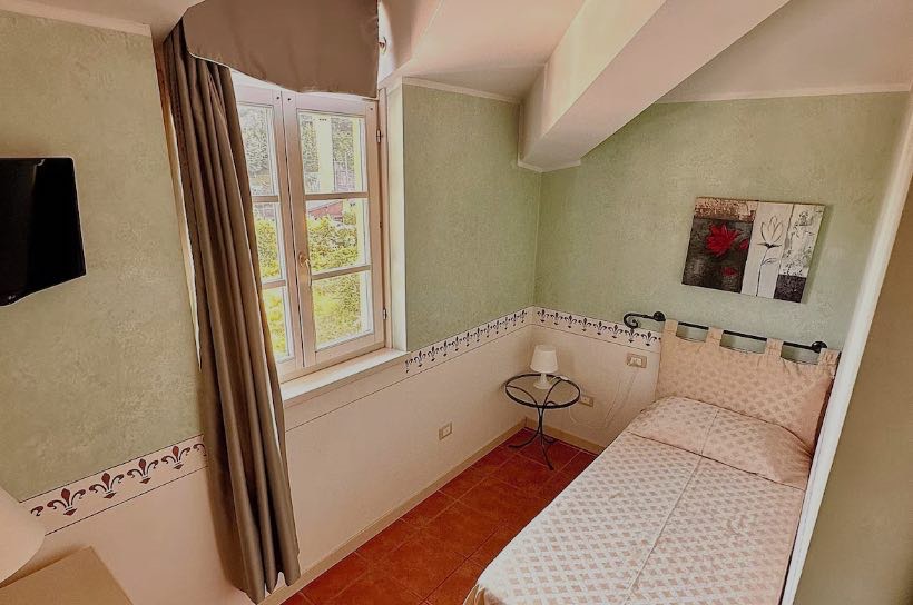 Single Room: a single bed beneath a window, soft green walls.