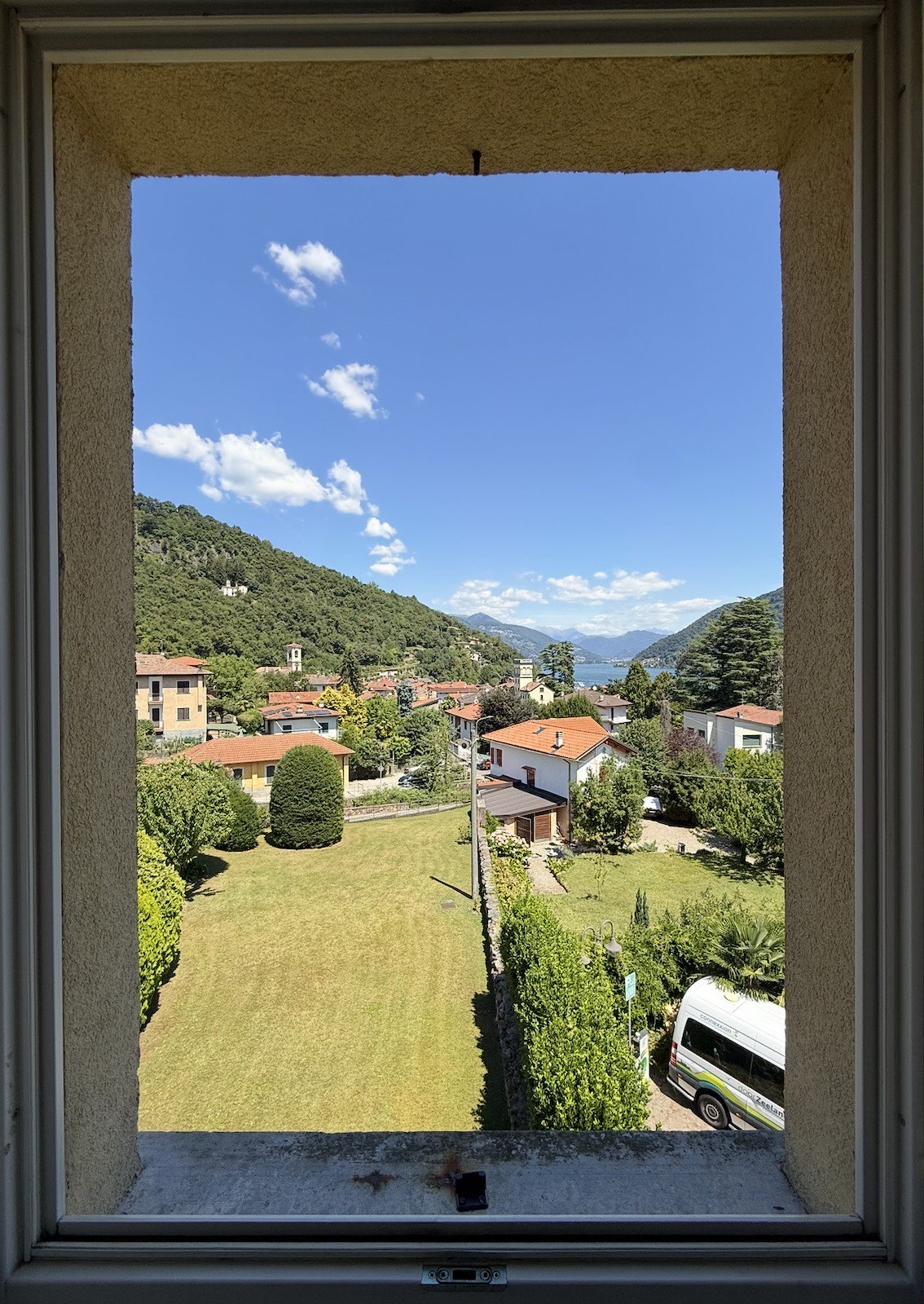 Smart Room: a tall window framing the garden, the village and the lake.