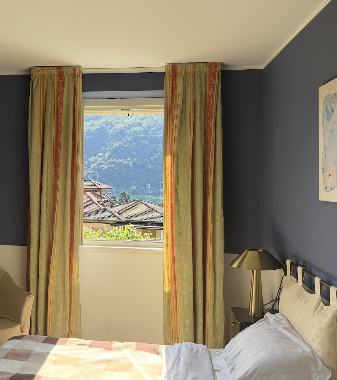 Superior Room: a blue room with long curtains and a window onto the wooded hill.