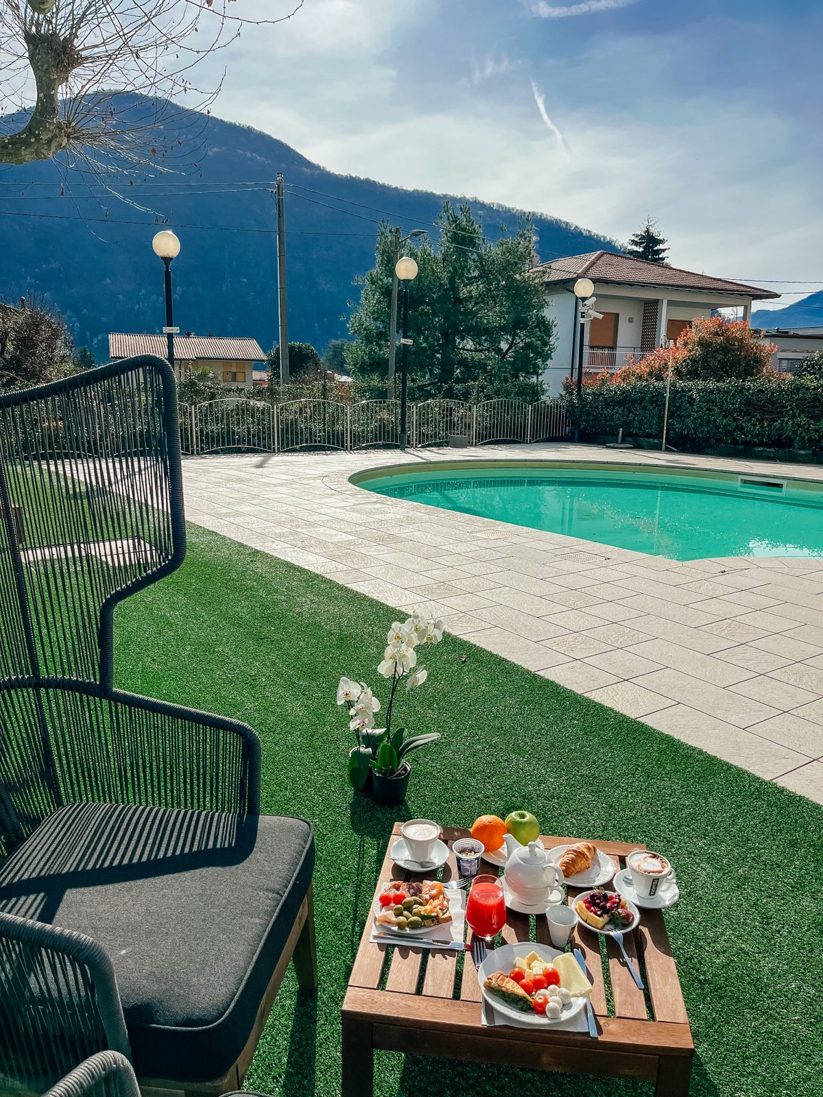 A garden armchair and a small breakfast table beside the pool, the mountains behind.