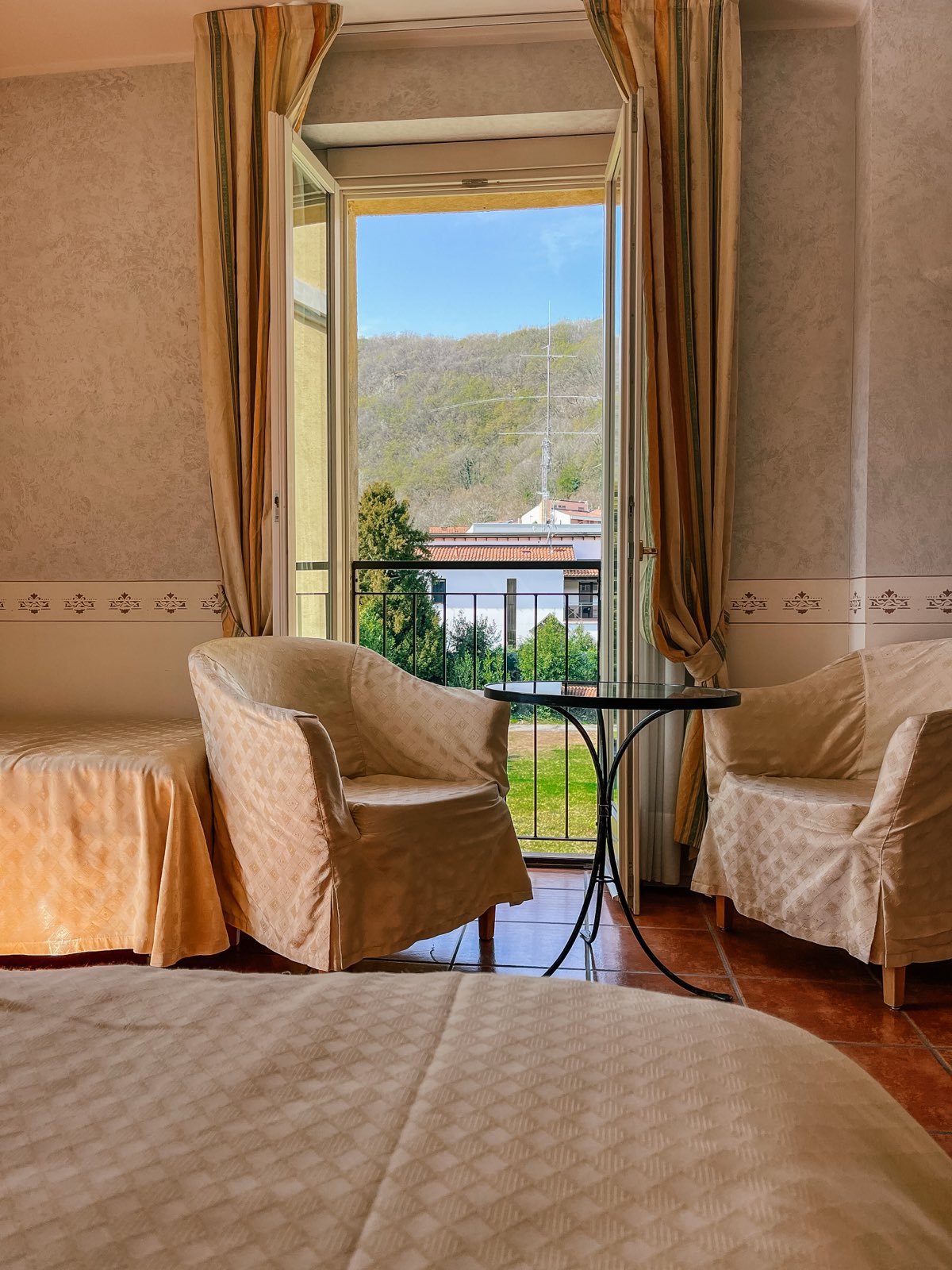 The same Balcony Room seen from the bed: two armchairs at the open balcony doors.