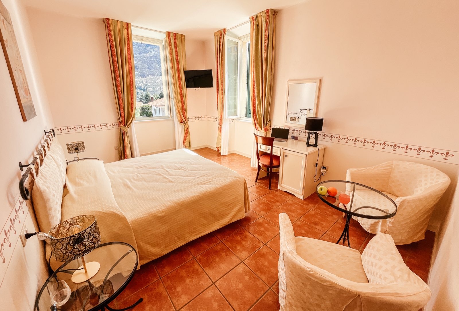 A bright double room with white armchairs and a glass table.